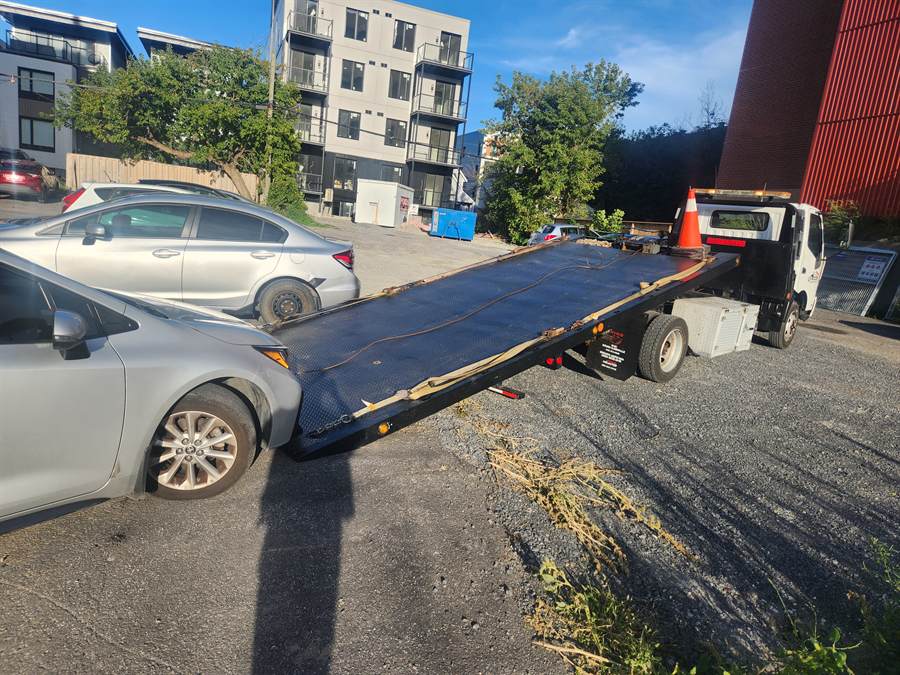 A silver sedan lined up at the tilted deck of the Kicks Towing flatbed