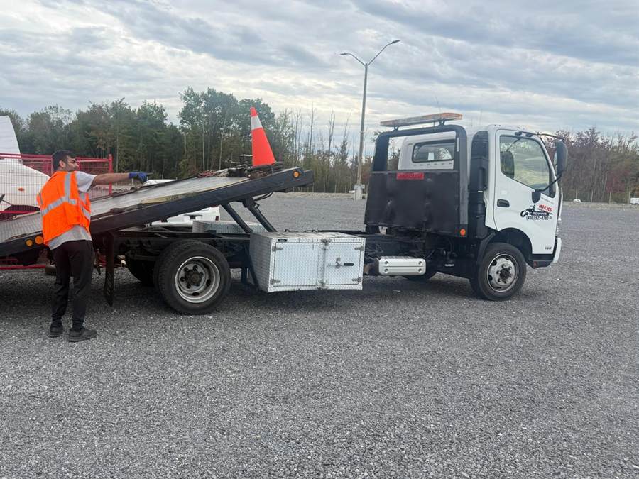 Kicks Towing operator in a safety vest working the flatbed controls